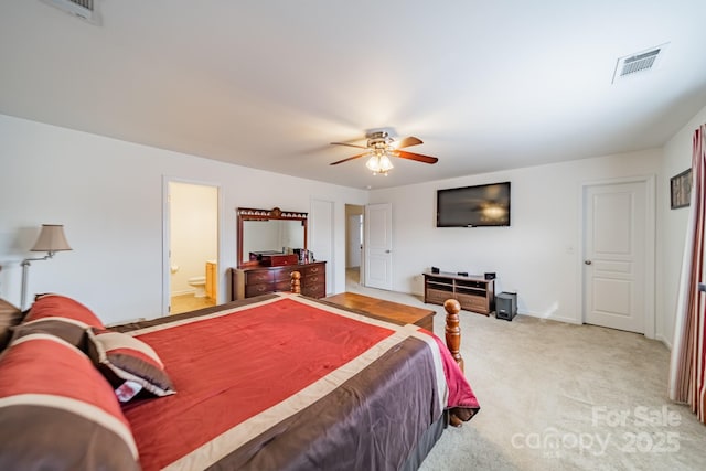 bedroom with ensuite bathroom, light carpet, and ceiling fan