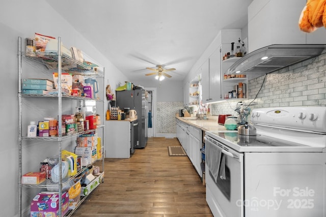 kitchen with electric stove, stainless steel refrigerator, premium range hood, dark hardwood / wood-style floors, and white cabinets