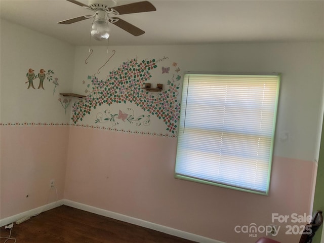 empty room with ceiling fan, a healthy amount of sunlight, and dark hardwood / wood-style floors