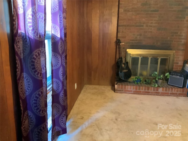 interior details featuring carpet flooring, a brick fireplace, and wood walls