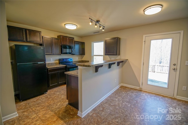 kitchen with dark brown cabinetry, a breakfast bar area, black appliances, and plenty of natural light