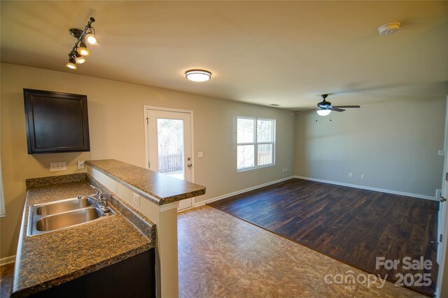 kitchen featuring dark wood-type flooring, dark brown cabinetry, sink, kitchen peninsula, and ceiling fan