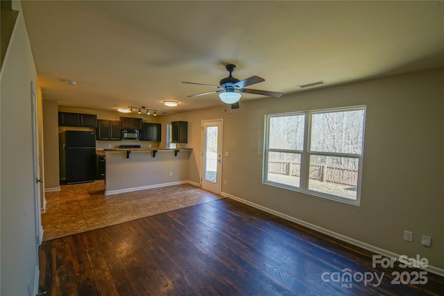 unfurnished living room featuring dark wood-type flooring, ceiling fan, and plenty of natural light