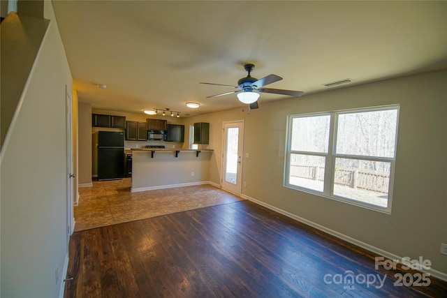 unfurnished living room with ceiling fan, dark hardwood / wood-style floors, and a healthy amount of sunlight