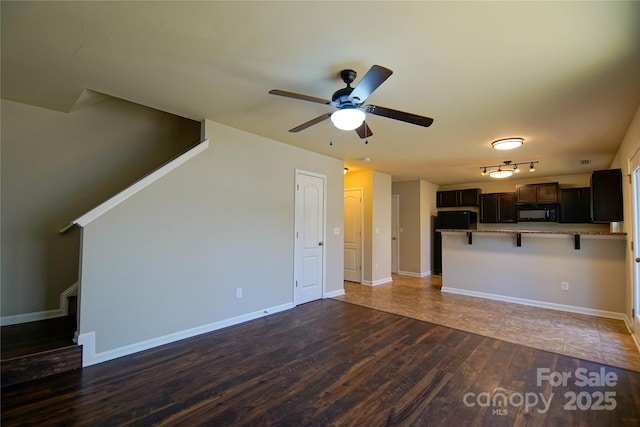 unfurnished living room with dark wood-type flooring and ceiling fan