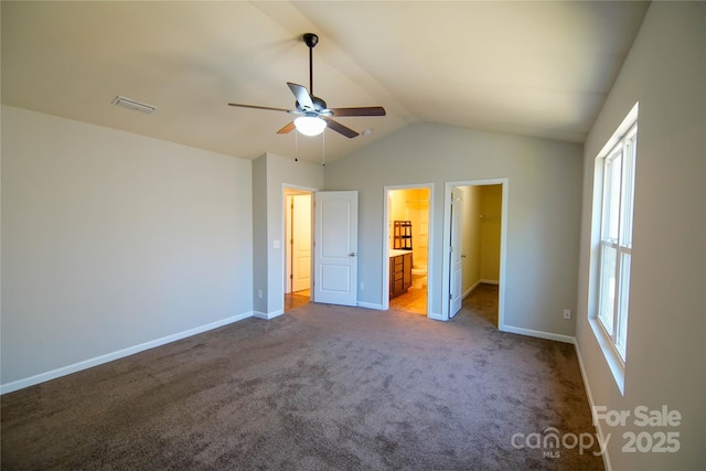 unfurnished bedroom featuring ensuite bath, a spacious closet, vaulted ceiling, ceiling fan, and carpet