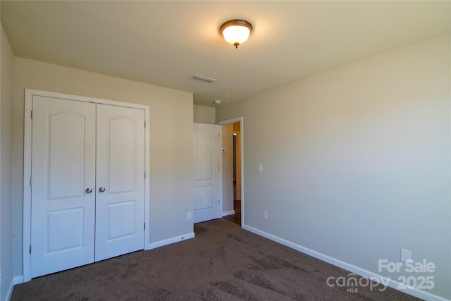 unfurnished bedroom with a closet and dark colored carpet