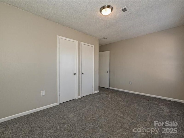 unfurnished bedroom with dark colored carpet and a textured ceiling