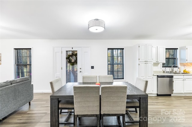 dining area with a healthy amount of sunlight, sink, and light hardwood / wood-style flooring