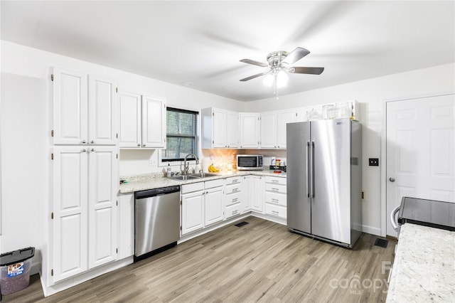 kitchen featuring appliances with stainless steel finishes, sink, white cabinets, and light wood-type flooring