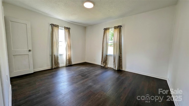 unfurnished room featuring dark hardwood / wood-style floors, a wealth of natural light, and a textured ceiling