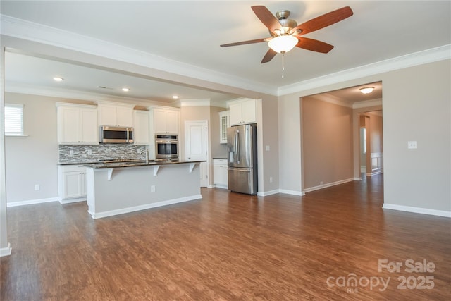 kitchen featuring white cabinetry, a kitchen breakfast bar, an island with sink, stainless steel appliances, and backsplash