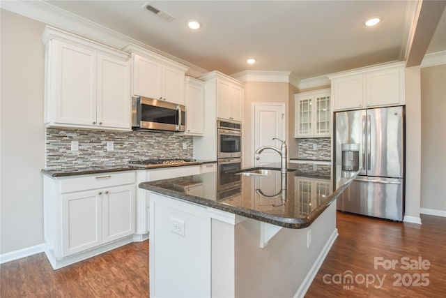 kitchen with white cabinetry, sink, decorative backsplash, stainless steel appliances, and a center island with sink