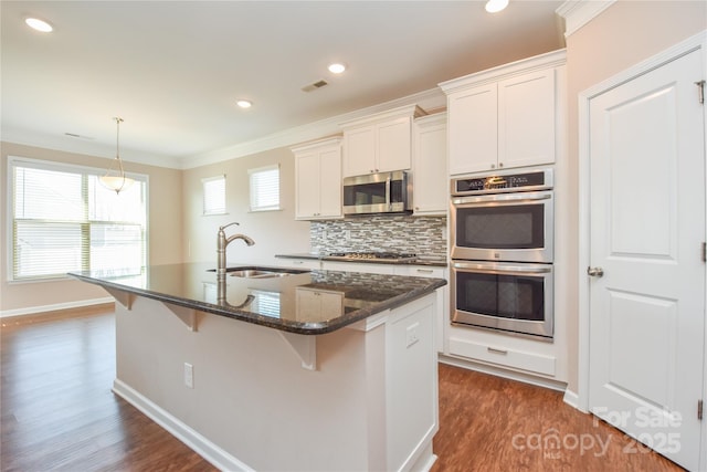 kitchen featuring sink, white cabinetry, dark stone countertops, stainless steel appliances, and a kitchen island with sink