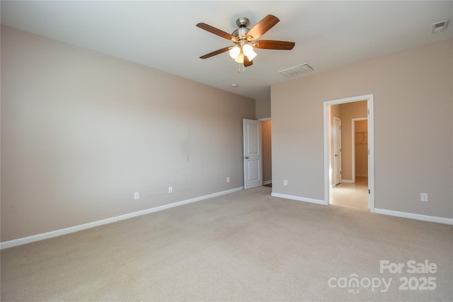 unfurnished bedroom with a walk in closet, light colored carpet, and ceiling fan