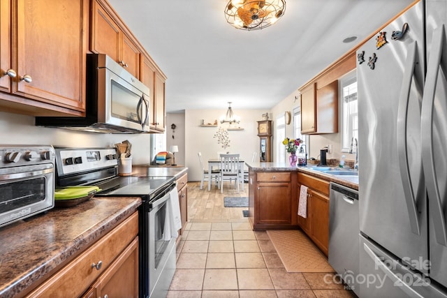 kitchen featuring light tile patterned flooring, sink, a chandelier, hanging light fixtures, and appliances with stainless steel finishes