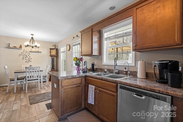 kitchen with pendant lighting, dishwasher, sink, light hardwood / wood-style floors, and kitchen peninsula