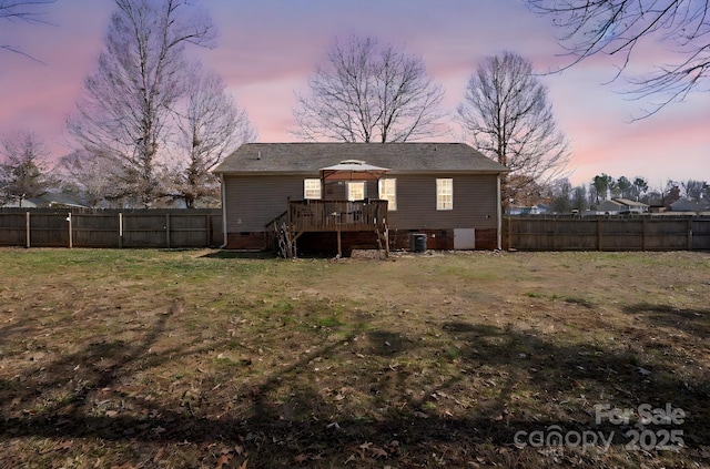 back house at dusk featuring a gazebo, cooling unit, a deck, and a lawn