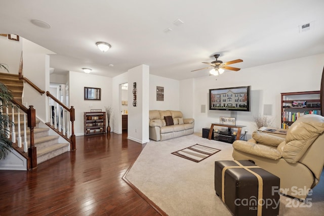 living room with dark wood-style flooring, visible vents, stairway, ceiling fan, and baseboards