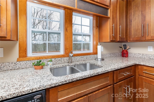 kitchen with dishwasher, sink, and light stone countertops