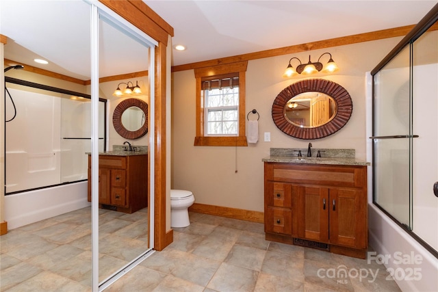 full bathroom featuring toilet, vanity, and shower / bath combination with glass door