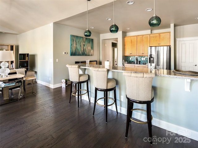 kitchen featuring stainless steel fridge with ice dispenser, decorative backsplash, hanging light fixtures, and light brown cabinets