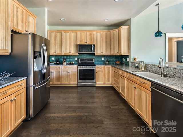 kitchen with appliances with stainless steel finishes, sink, dark hardwood / wood-style flooring, dark stone counters, and hanging light fixtures