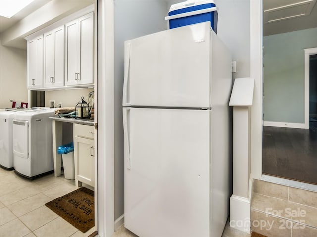 laundry room featuring washer and dryer, light tile patterned floors, and cabinets