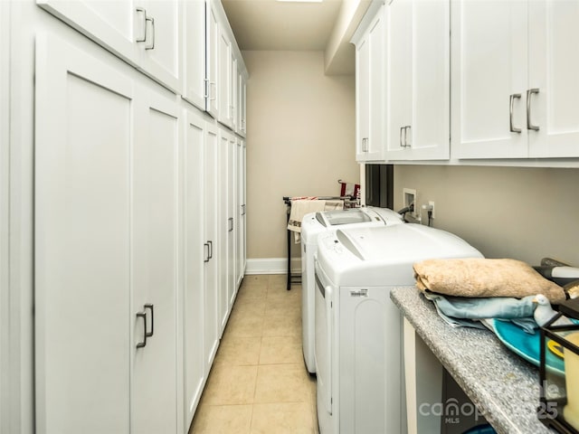 laundry room with light tile patterned floors, cabinets, and washing machine and clothes dryer