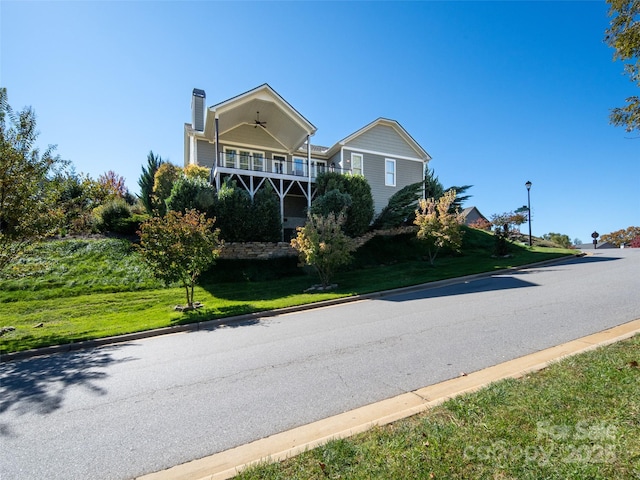 view of front of house featuring ceiling fan, a front lawn, and a balcony