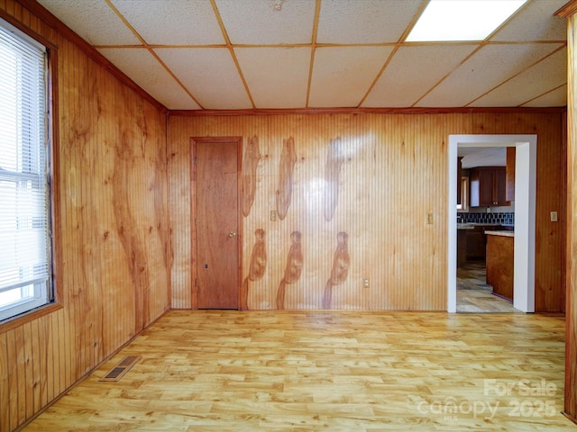 empty room with plenty of natural light, light hardwood / wood-style floors, and wood walls