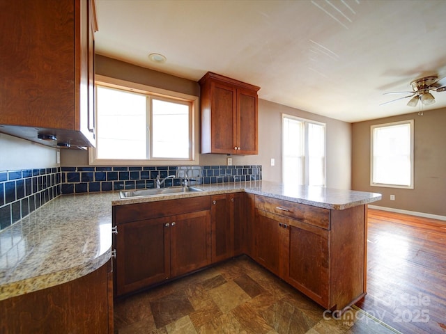 kitchen featuring tasteful backsplash, sink, kitchen peninsula, and ceiling fan