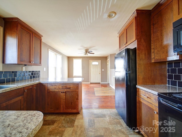 kitchen featuring light stone counters, kitchen peninsula, ceiling fan, decorative backsplash, and black appliances