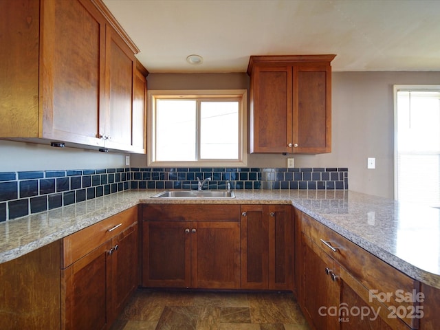 kitchen with light stone counters, sink, and backsplash