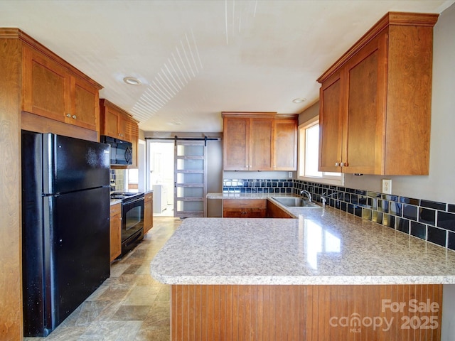 kitchen featuring tasteful backsplash, black appliances, sink, kitchen peninsula, and a barn door