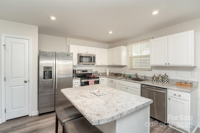 kitchen with stainless steel appliances, white cabinetry, a center island, and sink