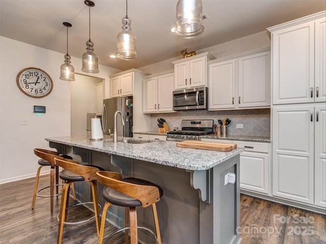 kitchen featuring white cabinetry, appliances with stainless steel finishes, an island with sink, and pendant lighting