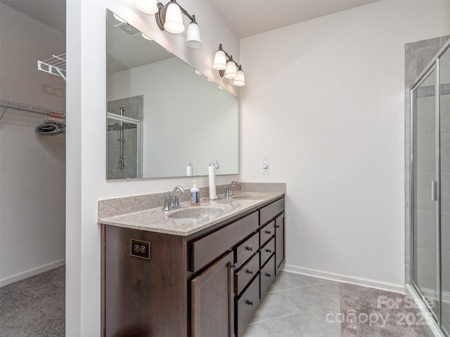 bathroom with a shower with door, vanity, and tile patterned flooring