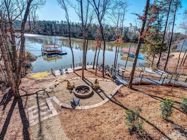 view of yard featuring a water view, a fire pit, and a boat dock