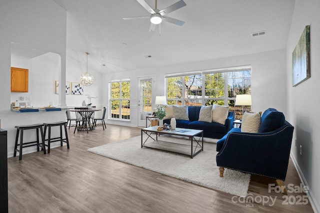 living room featuring hardwood / wood-style flooring, high vaulted ceiling, and ceiling fan with notable chandelier