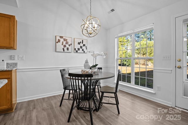 dining area with vaulted ceiling, light hardwood / wood-style floors, and a chandelier