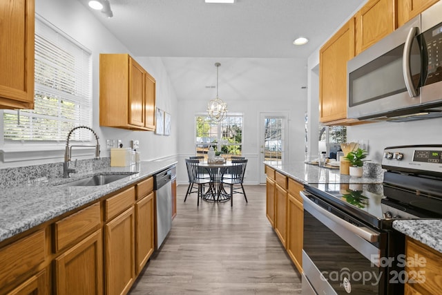 kitchen with a healthy amount of sunlight, stainless steel appliances, light stone countertops, and sink