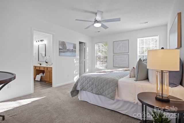 bedroom with light carpet, ceiling fan, a textured ceiling, and ensuite bathroom