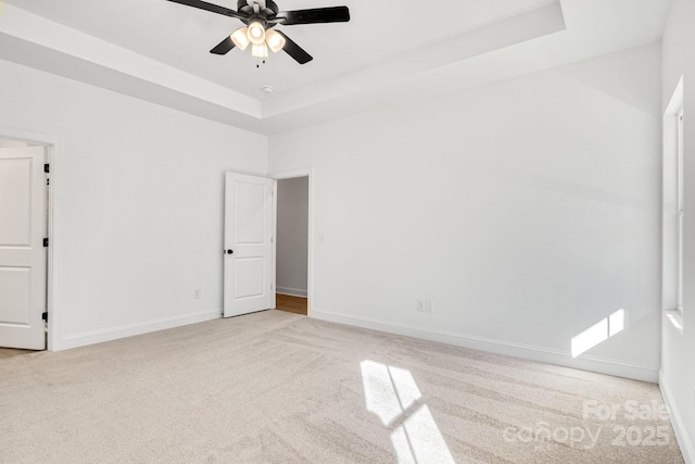 unfurnished room featuring light carpet, ceiling fan, and a tray ceiling