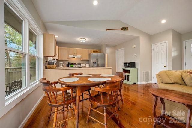 dining room with vaulted ceiling and wood-type flooring