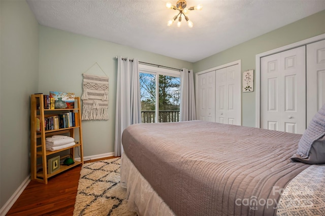 bedroom featuring multiple closets, access to exterior, dark hardwood / wood-style floors, and a textured ceiling