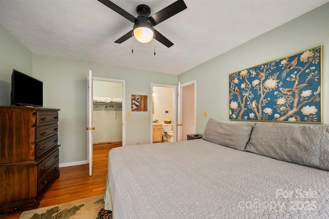 bedroom with hardwood / wood-style flooring, ceiling fan, ensuite bathroom, a spacious closet, and a closet