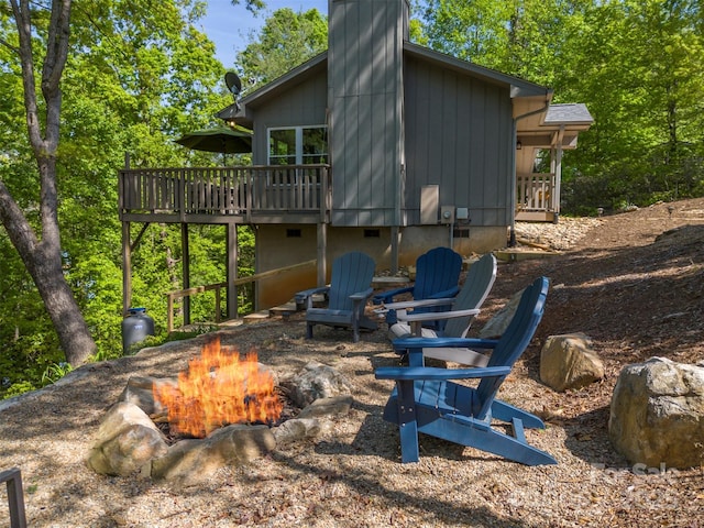 back of property featuring a fire pit and a deck