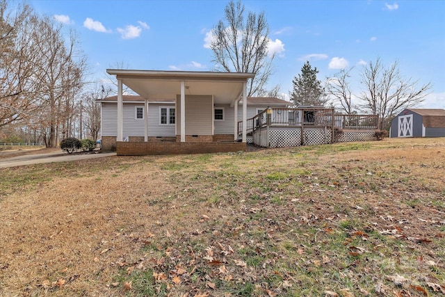 rear view of property featuring a yard, a storage unit, and a deck