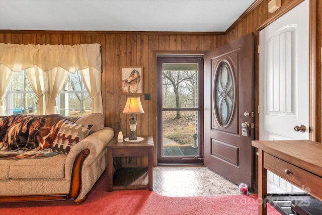 foyer entrance featuring crown molding, carpet flooring, and wooden walls